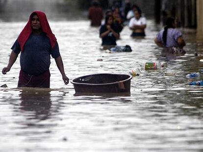 Varias personas caminan entre las aguas del río Suchiate, en la frontera entre Guatemala y México.