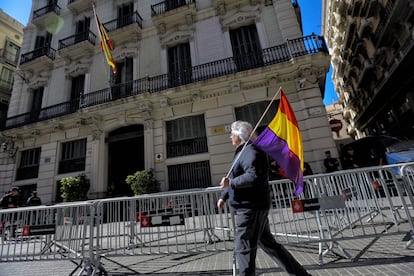 Una persona con una bandera republicana pasa esta mañana por delante de la Jefatura Superior de Policía de Cataluña en Via Laietana de Barcelona.