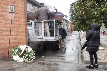 La cuadrilla utiliza un remolque para alcanzar los nichos situados en la fila más alta. Una mujer observa cómo entierran a su hermano, fallecido a los 60 años tras contagiarse de la enfermedad.