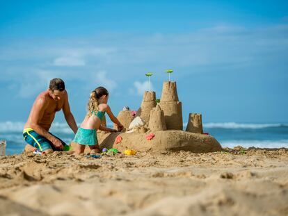 Un hombre y su hija construyen un castillo de arena en una playa de Hawai, en Estados Unidos,