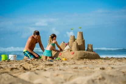 Un hombre y su hija construyen un castillo de arena en una playa de Hawai, en Estados Unidos,