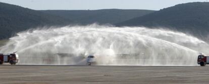 Dos camiones de bomberos bautizan el primer avión que operó en el aeropuerto Central de Ciudad Real.