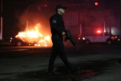 Un oficial de policía camina junto a un vehículo incendiado por miembros del Cártel Jalisco Nueva Generación, en Zapopan, Estado de Jalisco, el 9 de agosto de 2022.