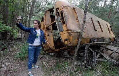 Una mujer se fotografía junto a un autobús abandonado, durante una visita guiada a Chernóbil (Ucrania). El creador de la miniserie ha enfatizado: "Si visita la zona, por favor recuerde que allí ocurrió una terrible tragedia. Compórtense con respeto por todos los que sufrieron y se sacrificaron".