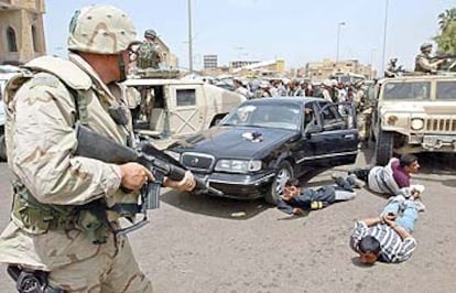Un policía militar estadounidense apunta con su arma a iraquíes detenidos por saqueo en el centro de Bagdad.