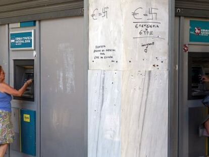 Dos ciudadanas sacan dinero de un cajero autom&aacute;tico en Atenas.