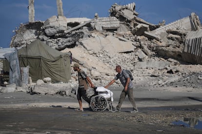 Dos hombres empujan una silla de ruedas con sacos de harina descargados de un convoy de ayuda humanitaria en Beit Lahiya, en el norte de Gaza.