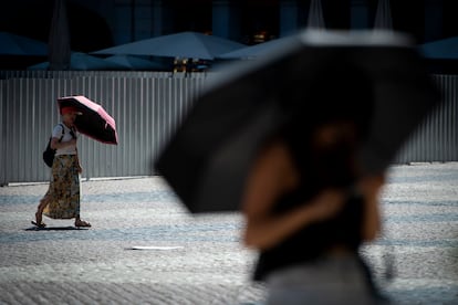 Dos mujeres se protegen del sol en el centro de Madrid, este viernes.