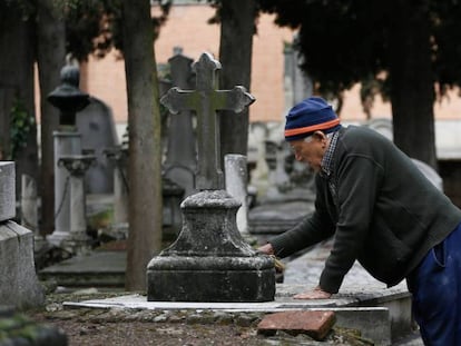 Urbano, de 78 a&ntilde;os, limpia una l&aacute;pida en el cementerio de la Almudena de Madrid.