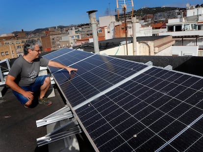 Eduard Moreno, ante los paneles fotovoltaicos que ha instalado en la cubierta del edificio donde vive, en el barrio de Gràcia de Barcelona en julio.