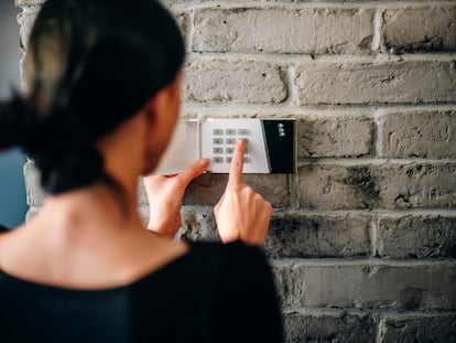 Una mujer marca el número de seguridad en un sistema de alarma.