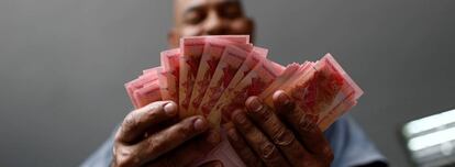 Un funcionario de un estacionamiento cuenta billetes de bolívar fuerte en Caracas.