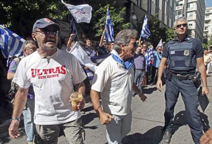 Griegos se manifiestan mientras esperan a los representantes de la troika frente al ministerio griego de Finanzas en Atenas.