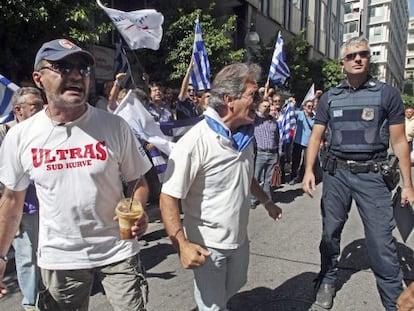 Griegos se manifiestan mientras esperan a los representantes de la troika frente al ministerio griego de Finanzas en Atenas.