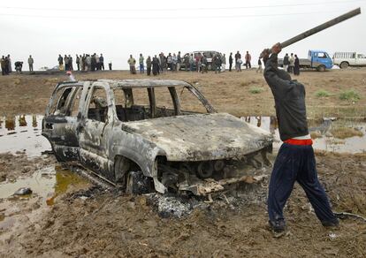 Un iraquí golpea los restos calcinados del coche en el que viajaban los agentes españoles.