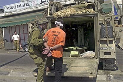 Un soldado israelí conduce a un palestino arrestado a una furgoneta en Hebrón.