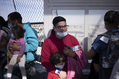Un hombre llora mientras aguarda con una niña y otros migrantes.