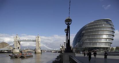 Varias personas pasean al lado del Tower Bridge y el City Hall de Londres.