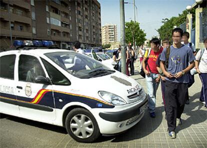 Un coche de la Polica Nacional, ayer a la salida del instituto de Orriols, a cuyas puertas se concentra un grupo que amenaza a estudiantes inmigrantes.