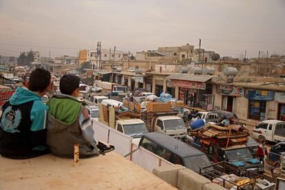 Dos niños observan la caravana de personas que huyen de la ciudad siria de Hazano, en el norte del país.