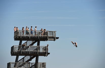 Un chico salta desde una torre de saltos, en la orilla del lago Ammersee, cerca de la aldea bávara de Utting, al sur de Alemania.