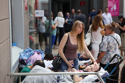 A woman accompanies a patient at a children's hospital attacked by Russian missiles, on Monday in kyiv.