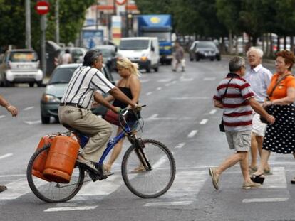 Un hombre carga en su bici con dos bombonas.