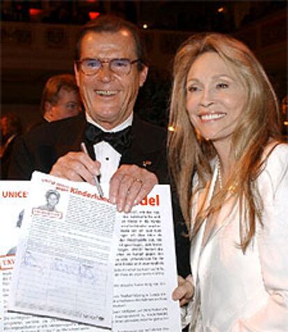 Roger Moore y Faye Dunaway, durante la gala benéfica de Unicef en Berlín, muestran la petición de firmas contra el tráfico de niños.