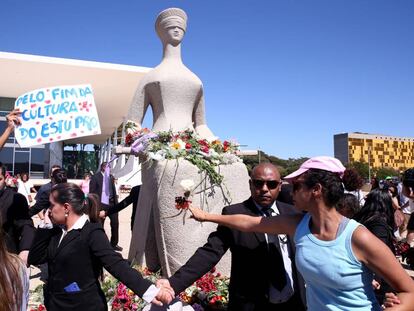 Mulheres protestam depositando flores na est&aacute;tua da Justi&ccedil;a, em Bras&iacute;lia