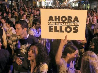 Uma jovem mostra um cartaz em rua próxima à praça Sol, durante o 15-M.