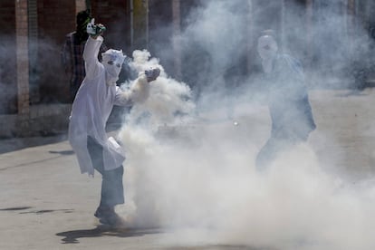 Un manifestante encapuchado de Cachemira lanza gas lacrimógeno a la policía india durante una protesta en Srinagar, India.