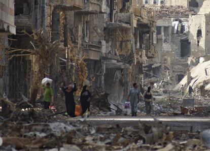 Residentes y un combatiente rebelde atraviesan una zona residencial devastada en Deir al Zor (este de Siria), el 7 de abril. 