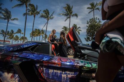 Dos jóvenes, junto a un coche deportivo en Miami Beach.