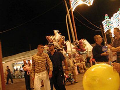 Un policía local de Ceuta lleva a un joven detenido por el recinto de la feria.