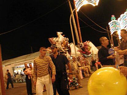 Un policía local de Ceuta lleva a un joven detenido por el recinto de la feria.