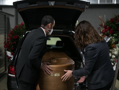 Dos conductores introducen un feretro en el interior de un vehiculo fúnebre en el tanatorio de Sancho de Avila (Barcelona).