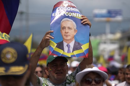 Un hombre sostiene una fotografía de Álvaro Uribe, en Cali, este jueves.