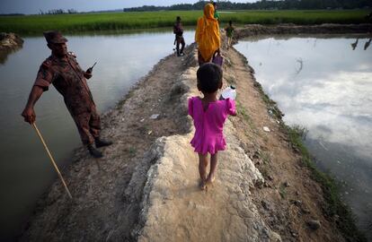 Una niña refugiada rohingya pasa frente a un guardia fronterizo mientras continúa su camino después de cruzar de Myanmar a Palang Khali, en Bangladés.