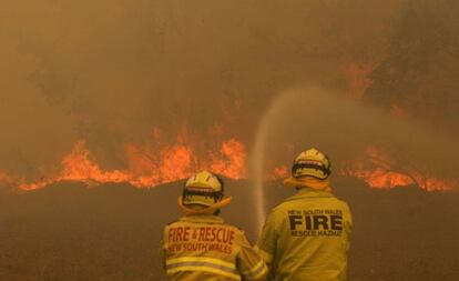 Dos bomberos trabajan este sábado en la extinción de un incendio forestal en Old Bar (Nueva Gales del Sur, Australia).