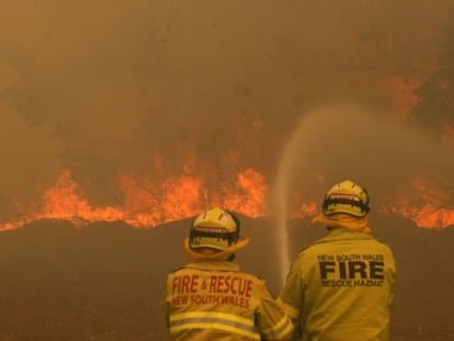 Dos bomberos trabajan este sábado en la extinción de un incendio forestal en Old Bar (Nueva Gales del Sur, Australia).