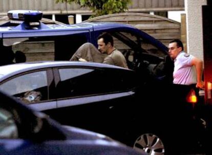 Asier Eceiza, con la cabeza cubierta, es trasladado a un coche policial tras ser detenido.