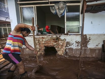 Casal tenta limpar a casa em Barra Longa.