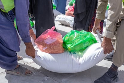 Las dos agencias de la ONU han mandado a Afganistán otros 100 equipos móviles de salud y nutrición más. Ya hay 168 equipos móviles que brindan un salvavidas para niños y madres en áreas de difícil acceso. En la imagen, dos hombres acarrean un saco de comida para sus familias en un puesto de distribución de alimentos de Herat.