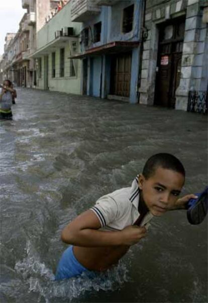 Habitantes de La Habana caminan con el agua a la cintura por una calle inundada de la capital cubana.