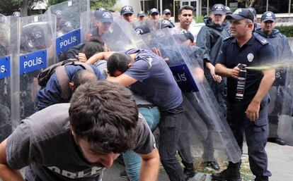 Un grupo de manifestantes se protege contra el gas lacrimógeno vertido por la policía durante una manifestación en contra de la construcción de un nuevo edificio para la embajada americana, frente a la actual, en Ankara (Turquía).