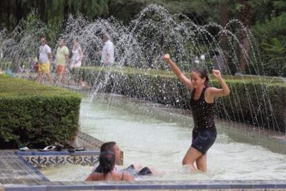 Varios jóvenes se bañan en una fuente del parque María Luisa de Sevilla.