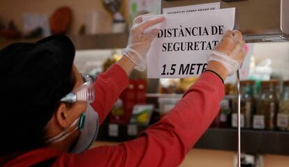 Una dona enganxa un cartell que demana mesures de seguretat.