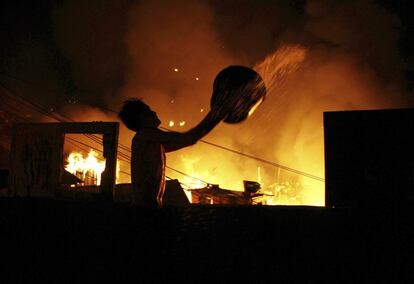 Desde última hora de la noche del lunes, Educandos, uno de los barrios más populares de la ciudad brasileña de Manaos, a orillas del río Negro —uno de los mayores afluentes del Amazonas—, ha sido devastado por un potente incendio que consumió más de medio millar de viviendas de madera y obligó a más de 2.000 personas a huir en busca de refugio. En la imagen, un hombre arroja un balde lleno de agua sobre una de las viviendas incendiadas en el vecindario de Educandos de Manaus, el 17 de diciembre.