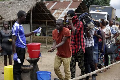 Un hombre toma la temperatura y ayuda a lavarse las manos correctamente a un grupo de hombres de la localidad de Massessehbeh, donde se acaba de poner fin a tres semanas de cuarentena.