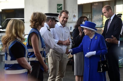 La reina Isabel II y el príncipe Guillermo saludan al personal de emergencia cerca de la escena del incendio.